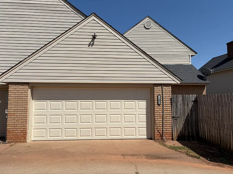 View of backyard with driveway with garage door and side gate.