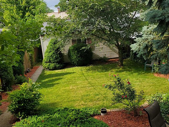 Fenced back yard with patio furniture, grill, and outdoor lighting.