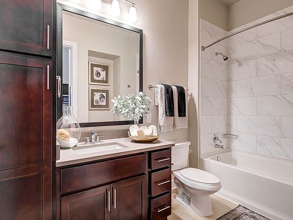 bathroom with tile surrounding soaking tub and espresso cabinetry