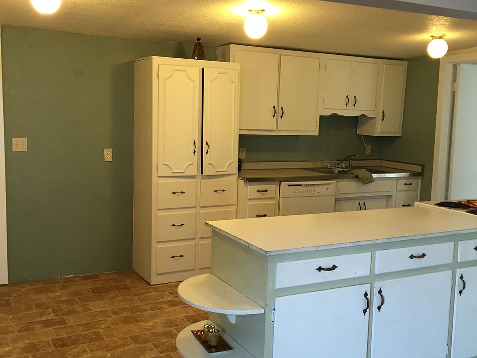 Kitchen has white cabinets, fresh painted walls, new dishwasher, stove, refrigerator, and an island.