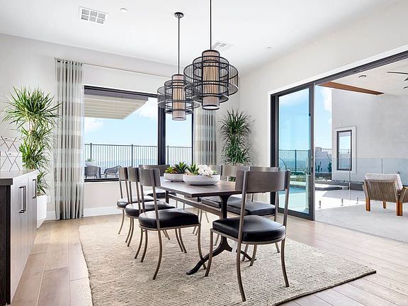 A modern and spacious dining room with a large wooden table, comfortable chairs, and stylish pendant