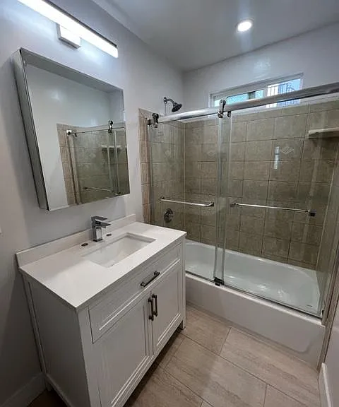 2nd full bath (hallway) with glass shower doors and large vanity and mirrored medicine cabinet
