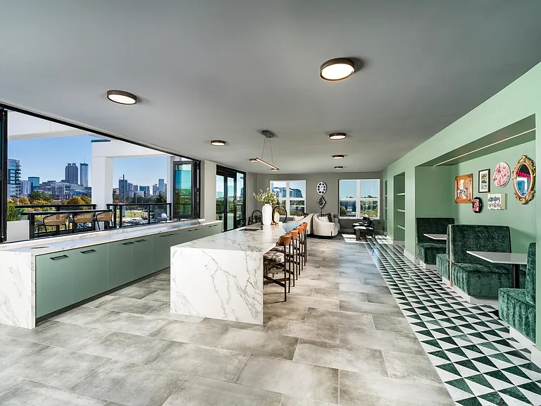 An open rooftop interior with a generous island, casual seating, and direct access to outdoor views, creating a natural flow for gathering or unwinding.
