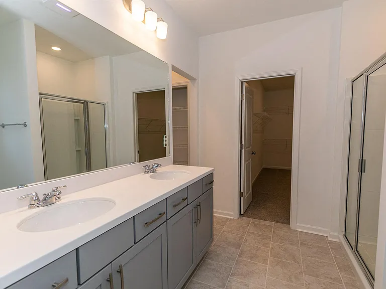 Primary bathroom with double vanity, walk-in shower and walk-in closet.