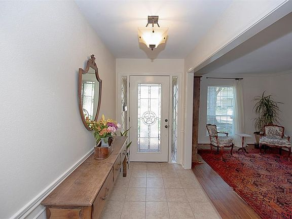A LOVELY BEVELLED GLASS DOOR OEPNS INTO A TILED FOYER WITH A VIEW INTO THE FORMAL LIVING ROOM.