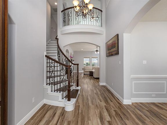 Impressive entry with soaring ceiling, wood tile flooring (2021), fresh paint (2021) and beautiful curved staircase.