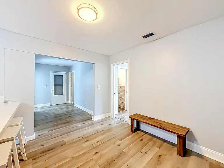 Open common area with durable wood-look flooring and overhead lighting, offering space for dining or a shared work nook.