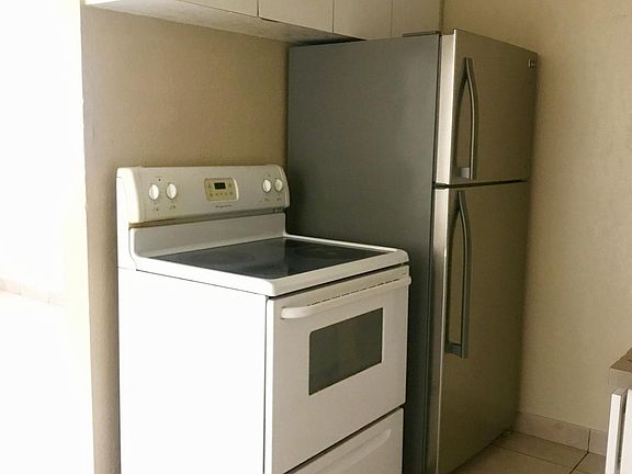 Stainless steel refrigerator, white stove(to be replaced with a stainless steel stove) and oven as well as white wood cabinets