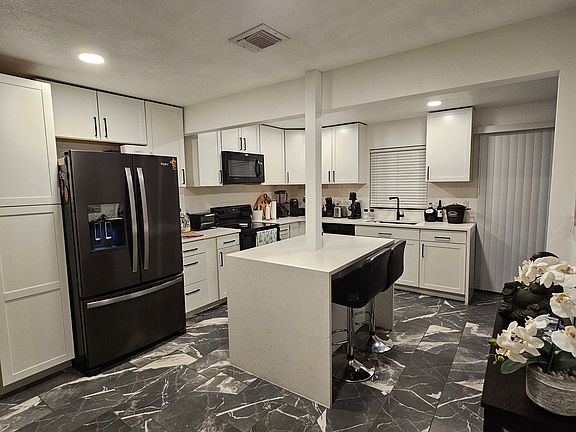 The kitchen features built-in Whirlpool appliances, including a refrigerator, dishwasher, stove, microwave, and garbage disposal. A deep farm-style sink adds both function and charm to the space.