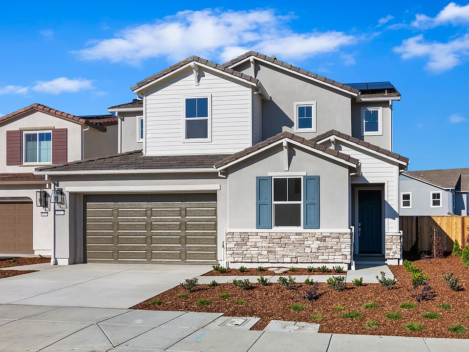 A two-story residential house with a garage, surrounded by landscaped yards and a clear blue sky wit
