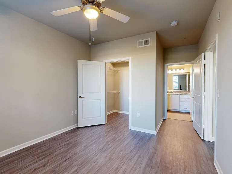 Spacious apartment bedroom with large closet, attached bathroom, and wood-style flooring.