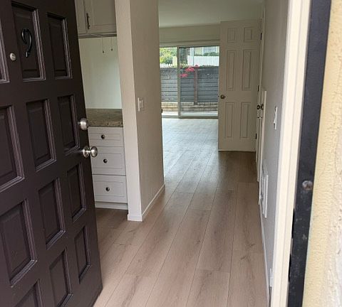 Front entrance with kitchen to the left with bar seating, living room and patio beyond. Powder room, under stairs storage and stairs to the bedrooms to the right (not visable in this picture).