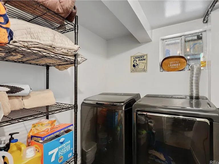 Shared laundry with large capacity washer/dryer and two shelving racks.