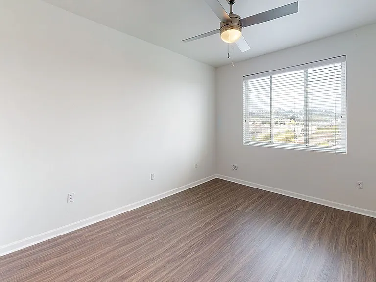 Spacious apartment bedroom with wood-style flooring.