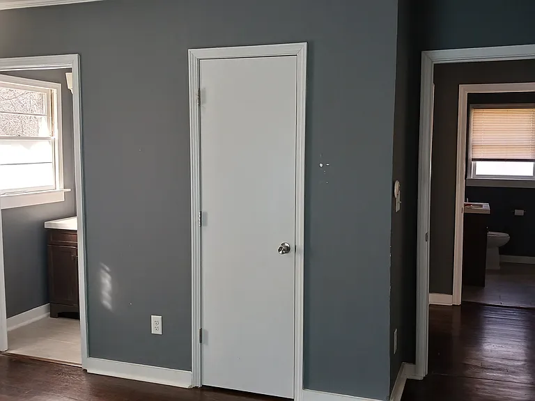 Bedroom view to half-bath (on left), closet (middle), and hallway leading to main bath (on right).