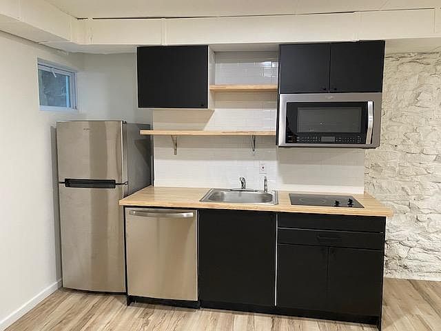 European style kitchen with open butcher block shelving & brand new appliance package: convention oven microwave, two-burner induction cooktop, dishwasher and refrigerator. Sorry bakers, no oven in unit.