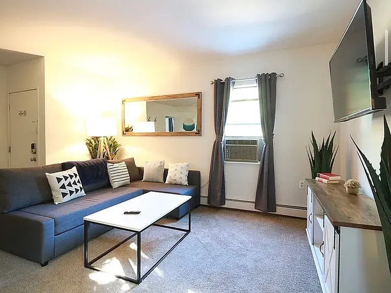 Living room. The unit is offered unfurnished; furnished photo included to provide a sense of the room's scale and layout possibilities.