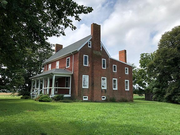 Farmhouse with front porch and main entrance from right side yard.