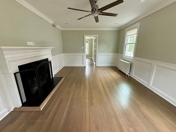 Formal living room with a fireplace and ceiling fan that leads to a sitting room