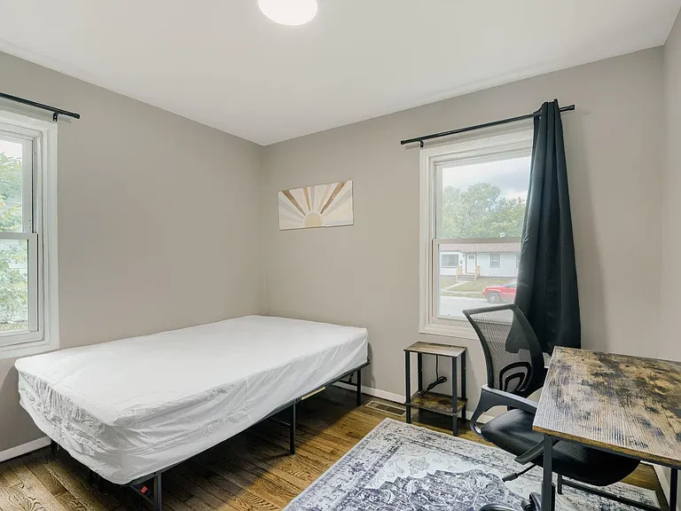 Private bedroom with two windows for natural light, a comfortable bed, and a dedicated desk area for work or study.