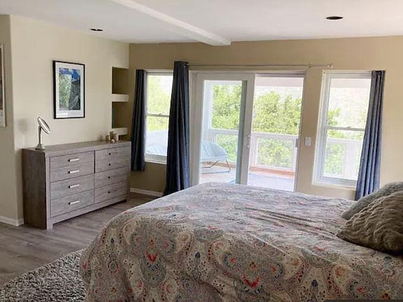 Spacious, furnished bedroom with dresser and sliding doors to the deck
