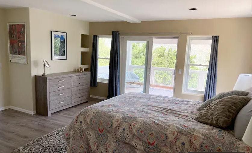 Spacious, furnished bedroom with dresser and sliding doors to the deck