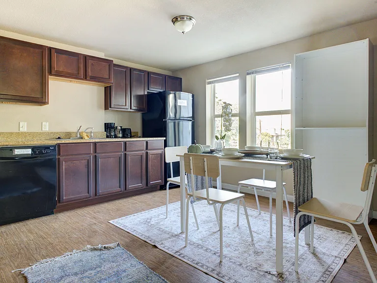 Eat-in kitchen with ample cabinet storage, full-size appliances, and a dining nook set beside two large windows.