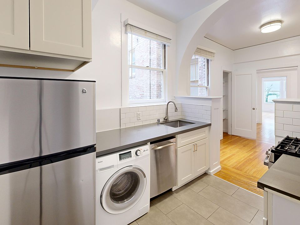 Modern kitchen featuring stainless steel appliances, cabinets, and a sleek countertop with ample natural light from windows.