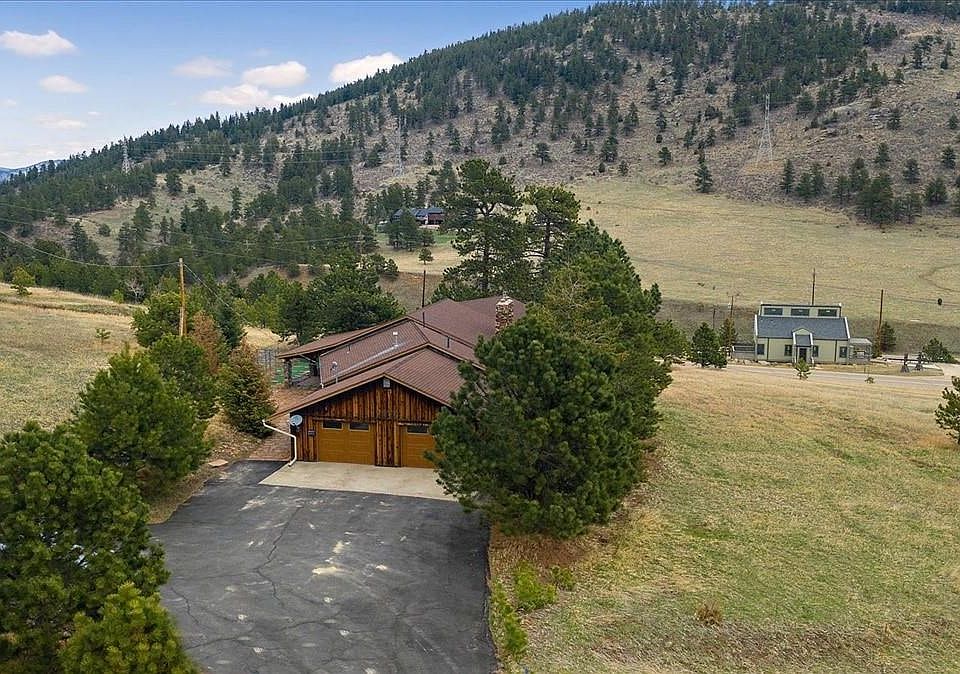 Front of house showing two car garage and driveway. Across the valley you can see the Floyd Hill Trail System.