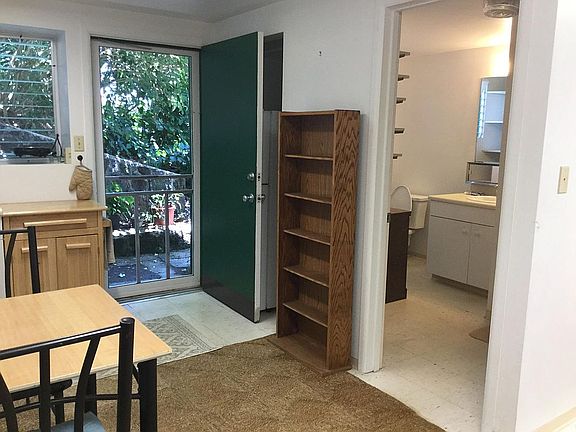 The fridge is in a recessed area behind the green door.