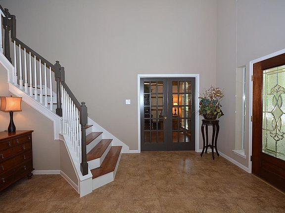 The 2-story entry is breathtaking, showing off the wooden stairway and a glimpse into the study thro
