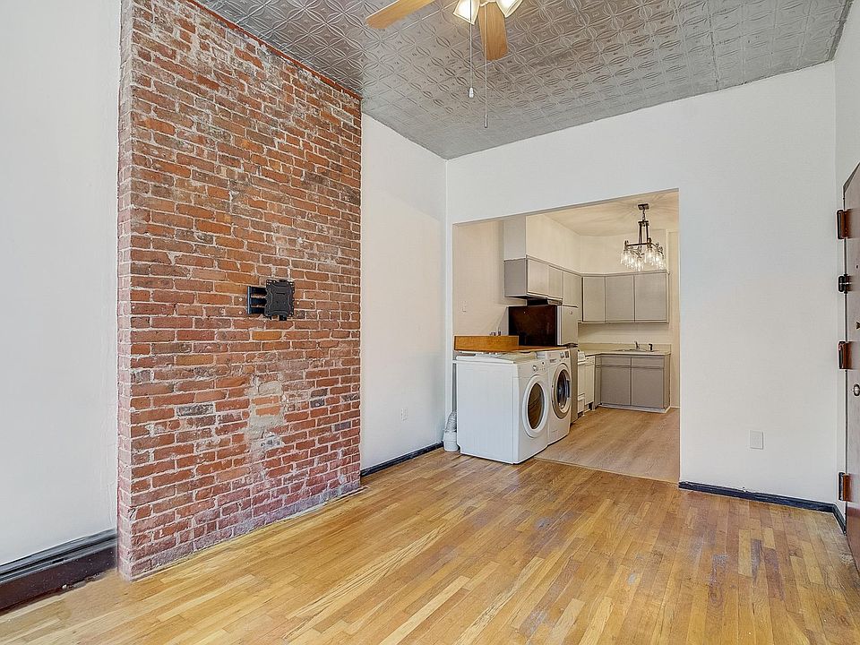 Sunny living space featuring exposed brick wall and ceiling fan.