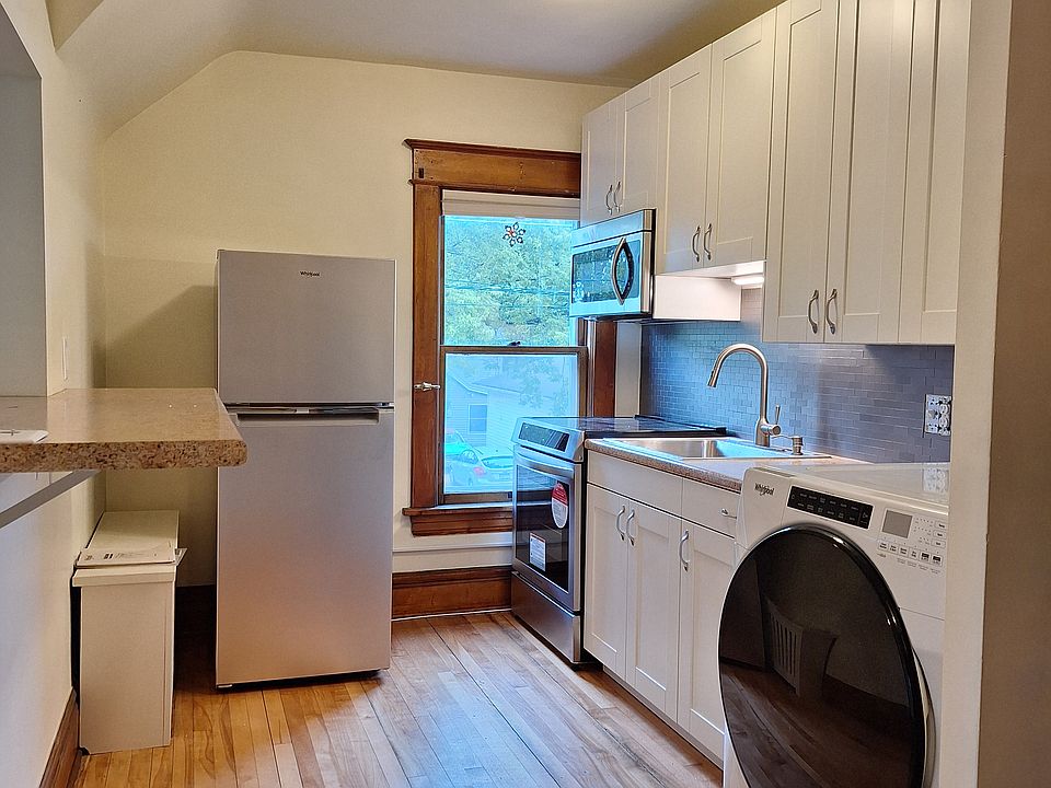 Kitchen - everything new: cabinets, countertops, induction range, fridge, microwave, washer/dryer combo. Breakfast bar on left.