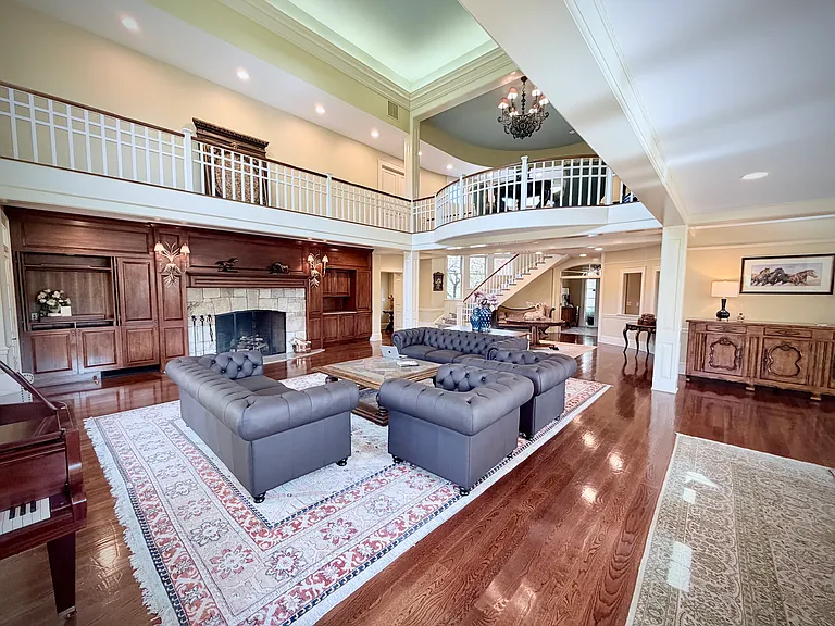 View of the richly decorated great room with seating for up to seventeen, a massive stone fireplace, and a grand piano.