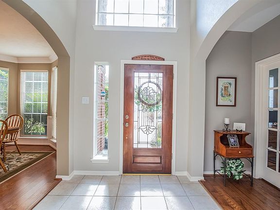 The entry is flanked by solid wood flooring at the dining and study areas with beautiful light filling the foyer through the arched windows and leaded glass door.