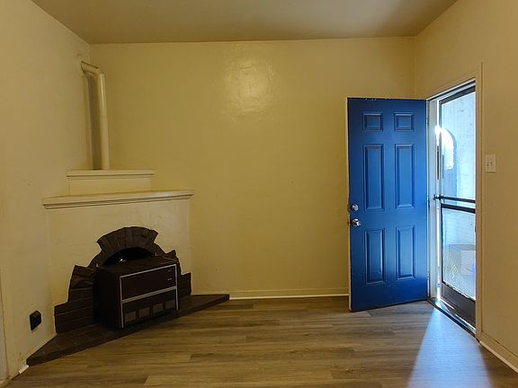 Living room has new plank floors and a heater in a converted fireplace.