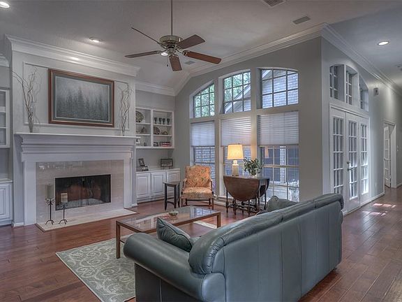 Living room has double crown molding, wood burning gas starter fireplace, wide plank wood flooring & pocket lighting