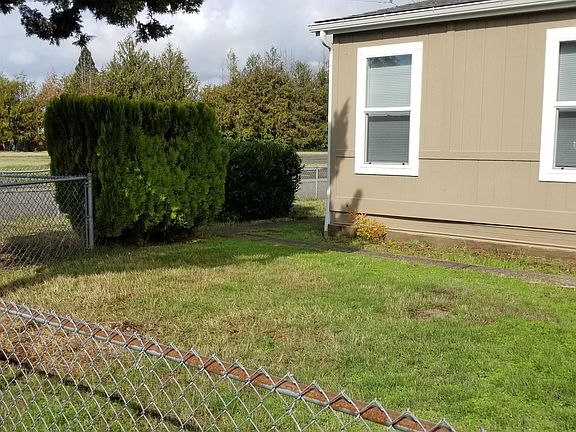 Fenced front yard with large trees.