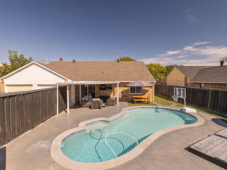 Go swimming in the pool with sun loungers, an umbrella, a floaters rack, pool lights, a basketball hoop as well as a beautiful view of the property in this fully-fenced yard.