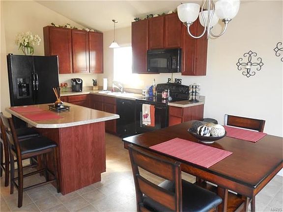 Cherry tone tall cabinets with breakfast bar and dining area.