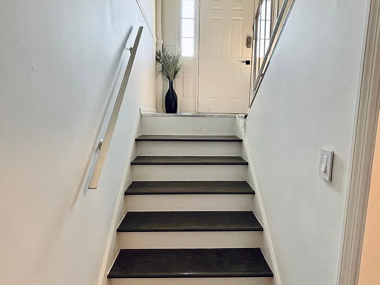 Clean stairwell with contrasting tread steps, sturdy handrails, and a landing by the entry with sidelights for daylight.