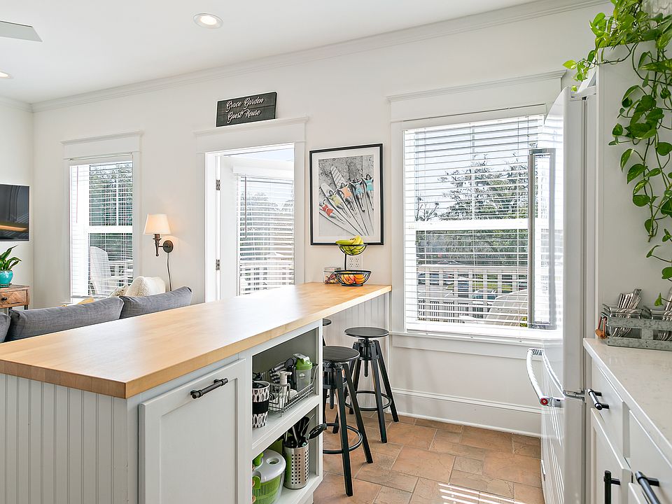Sunny kitchen and living room with huge butcher block island for seating, storage and hidden trash/recycling pull out.