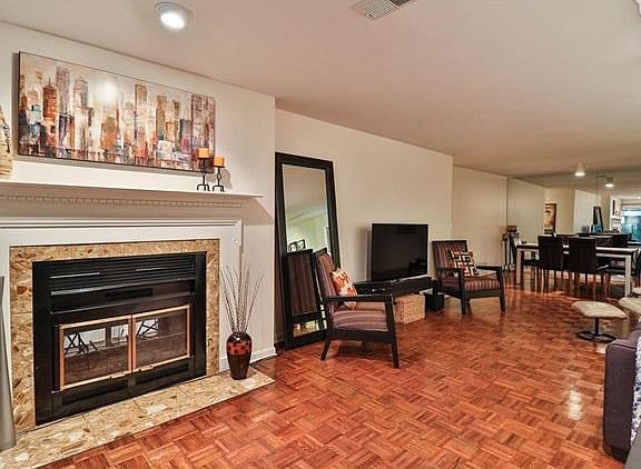 Fireplace and view of the living room and dining area with wall of mirrors