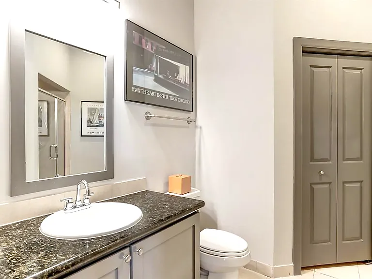 Full size guest bathroom with glass shower door, granite countertop, closet with door, and washer and dryer