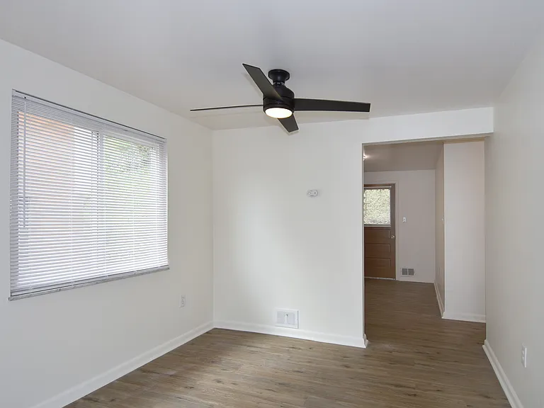 Separate dining room is freshly painted with all-new luxury vinyl plank flooring, new mini-blinds, and stylish ceiling fan.