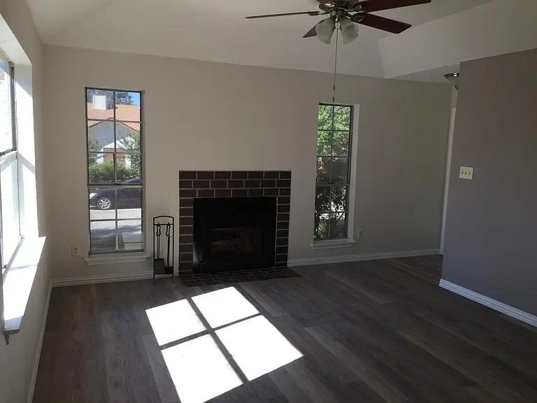 Den with fireplace, updated flooring and new ceiling fan.