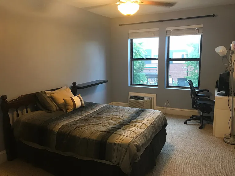 Furnished second bedroom with plenty of natural light, full-sized bed, and desk
