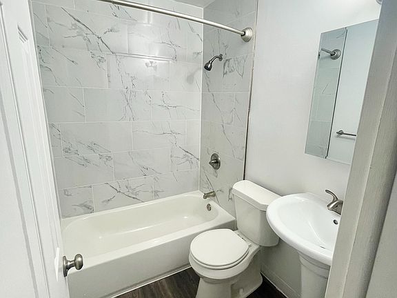 Elegant bathroom featuring a modern design with marble-style tiles, a cozy bathtub, and sleek fixtures.