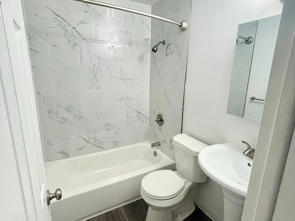 Elegant bathroom featuring a modern design with marble-style tiles, a cozy bathtub, and sleek fixtures.