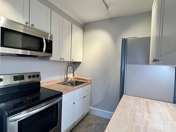 Renovated kitchen with fresh cabinets, butcher block counters and stainless steel appliances